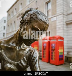 Londra, Regno Unito - 5 gennaio 2023: Statua in bronzo di una ballerina femminile con le iconiche caselle telefoniche londinesi sullo sfondo. All'esterno del Royal Opera House, L Foto Stock