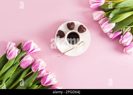 composizione con un bouquet di tulipani e una tazza di caffè su sfondo rosa. vista dall'alto. layout piatto. il concetto di vacanza Foto Stock