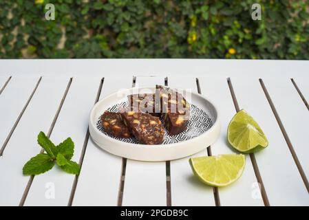 Salsiccia di cioccolato a fette servita su un tavolo di legno bianco vista laterale primo piano Foto Stock