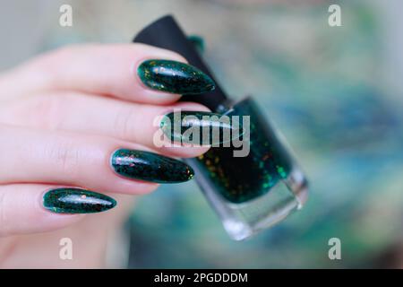 Mano di donna con unghie lunghe e smalto verde scuro per unghie Foto Stock