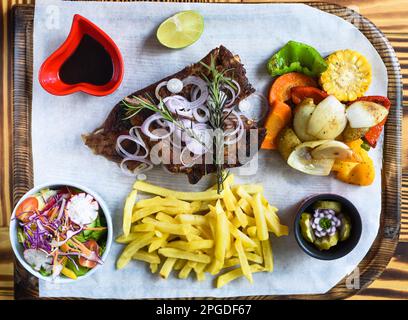 Costolette di maiale affumicate alla griglia con patatine fritte e salsa di soia e insalata su tavola di legno Foto Stock