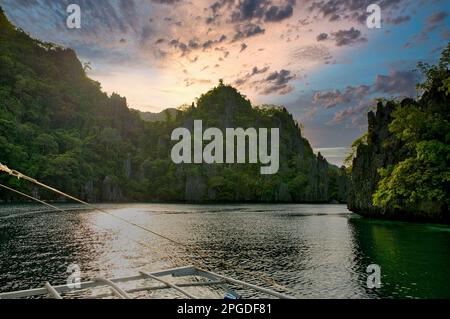 Una baia con rocce maestose a Coron, Palawan nelle Filippine che sono sovra-cresciute di arbusti e bastone fuori dall'acqua. Foto Stock