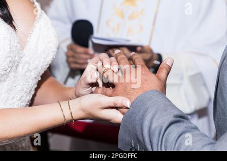 Primo piano, mani della sposa che collocano l'anello di nozze su suo marito il giorno di nozze. Foto Stock