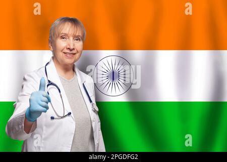 Donna medica matura sorridente indiana che tiene stetoscopio su bandiera di sfondo India Foto Stock