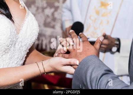 Primo piano, mani della sposa che collocano l'anello di nozze su suo marito il giorno di nozze. Foto Stock