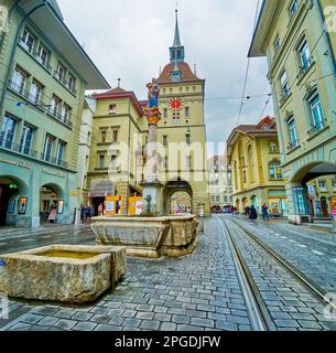 BERNA, SVIZZERA - 31 MARZO 2022: La torre di Kafigturm e la fontana medievale Anna-Seiler-Brunnen in via Marktgasse, il 31 marzo a Berna, Svizzera Foto Stock