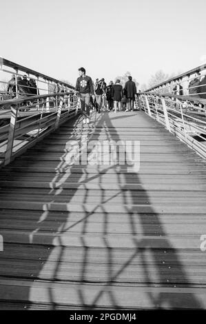 PARIGI, FRANCIA - 12 MARZO 2016: Adolescenti e turisti parigini sul ponte pedonale Solferino sulla Senna vicino al Museo d'Orsey. Un gioco di luce Foto Stock