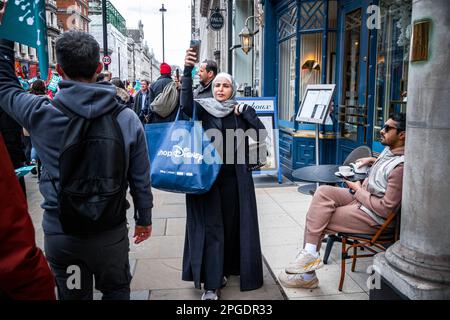 Londra, Regno Unito. 15th marzo, 2023. L'orologio di passerby mentre la demo si fa marcia. Manifestanti al più grande demo da quando gli scioperi sono iniziati. La protesta del Budget Day nel centro di Londra. Migliaia di persone hanno marciato per le strade verso Trafalgar Square, tra cui insegnanti, medici in formazione e funzionari pubblici, tutti in battuta per una retribuzione migliore e migliori condizioni di lavoro. In totale circa mezzo milione di lavoratori del settore pubblico in tutto il paese hanno superato la retribuzione. Foto Stock