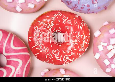 Ciambelle con smalto rosso e rosa, vista dall'alto. C'erano tantissime ciambelle, cibo squisito e dolce Foto Stock