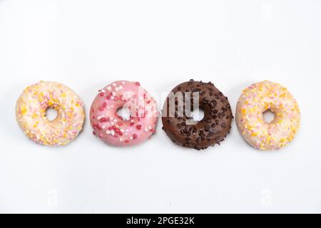 Quattro ciambelle in fila - bianco, rosa e cioccolato su uno sfondo bianco vista dall'alto Foto Stock