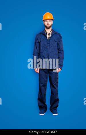 Ritratto integrale con gambe di un bel riparatore virile in uniforme blu, isolato su sfondo grigio, guardando la telecamera Foto Stock