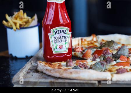 Bootle di Heinz ketchup e pizza in stile rustico sul tavolo di legno Foto Stock