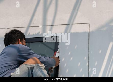 Il lavoratore installa la finestra con il bordo in silicone intorno allo spazio nel palazzo. Foto Stock