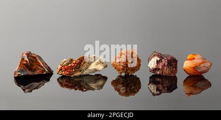 Gruppo di pietre e minerali disposti in una fila che include Vanadinite su Barite, Aragonite Sputnik, Erythrite cristalli, Mahogany Obsidian e Carnelian Foto Stock