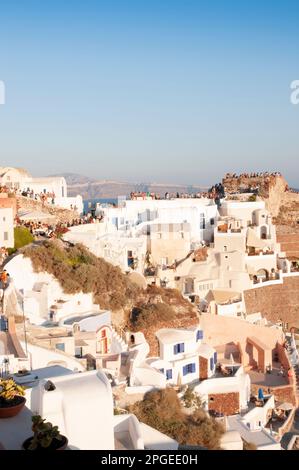 La gente gode di uno splendido tramonto sul Mar Egeo dai tetti delle case bianche di Oia, Santorini. Le tonalità rosa, arancione e viola colorano il cielo come Foto Stock