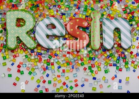 Cumulo di granuli multicolore in resina plastica su sfondo bianco con lettere in resina font Foto Stock