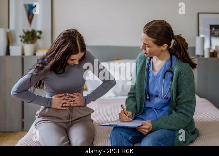 Ragazza adolescente con mal di stomaco, giovane medico che la esamina. Foto Stock