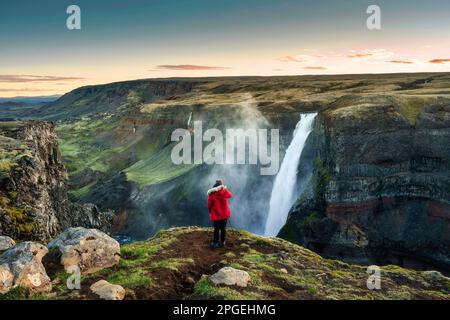 La maestosa cascata Haifoss scorre nel canyon vulcanico e il viaggiatore scatterà una foto tra le Highlands islandesi in estate in Islanda Foto Stock