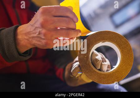 Uomo caucasico utilizzando nastro biadesivo primo piano foto. Foto Stock