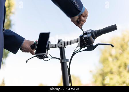 Hippster uomo d'affari pendolari con bicicletta elettrica in viaggio per lavorare in città. Un nuovo modo di trasporto alternativo e moderno. Bici elettrica ecologica. Foto Stock