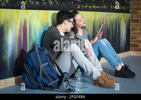 Studenti universitari con tablet digitale di fronte alla Graffiti Wall School, Baviera, Germania Foto Stock