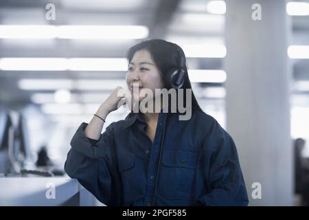 Donna d'affari che ascolta musica con le cuffie, Friburgo im Breisgau, Baden-Württemberg, Germania Foto Stock