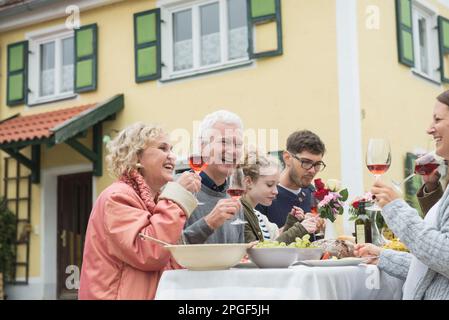 Famiglia e amici che si divertano a festa all'aperto in casa colonica, Baviera, Germania Foto Stock