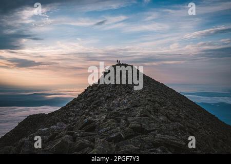 Due piccole figure si trovano sulla cima del monte Katahdin, Maine, all'alba Foto Stock