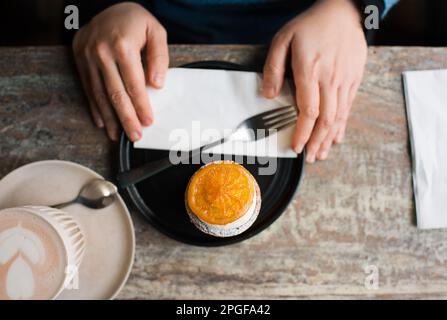 persona che tiene il piatto con una torta su un piatto in un caffè Foto Stock