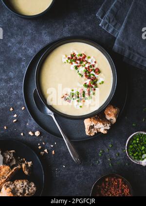 Testa di ciotola di zuppa di porro di patate guarnita su sfondo nero. Foto Stock