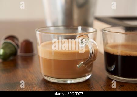 Tazze di latte e caffè nero con capsule espresso Foto Stock