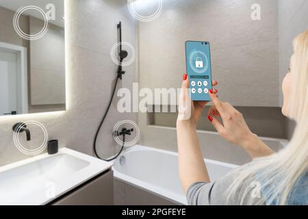 Mani femminili che tengono il telefono con la schermata Home intelligente dell'app nella stanza Foto Stock