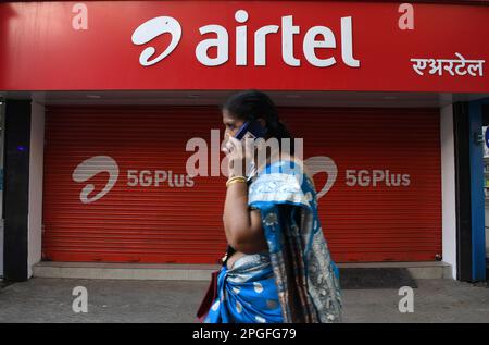 Mumbai, India. 22nd Mar, 2023. Una donna che comunica con un telefono cellulare passa davanti al negozio Airtel di Mumbai. Airtel offre dati illimitati ai suoi 5G clienti in 26 città. Esso coprirà l'intero paese, gli utenti rurali e urbani entro la fine di marzo 2024. (Foto di Ashish Vaishnav/SOPA Images/Sipa USA) Credit: Sipa USA/Alamy Live News Foto Stock