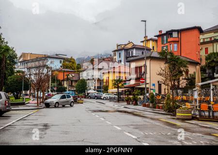 Città di Locarno e nebbia e nuvole basse nella montagna dietro. Autunno nel sud della Svizzera. Auto nei parcheggi per le strade . Nessuna gente. Foto Stock