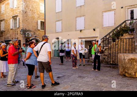 Turisti a Budva, Montenegro. La guida del tour chiede loro di riunirsi intorno a lei. Foto Stock