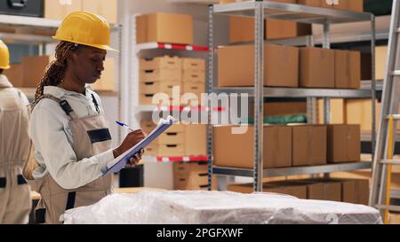 Team di depot che parla di spedizione di consegna nello spazio del magazzino, guardando le merci in pacchi. Diverse donne che controllano la merce e i prodotti in magazzino. Scatto con cavalletto. Foto Stock