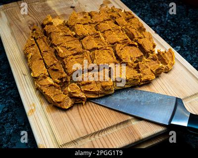 Dolci fatti in casa per cani di zucca, disposti su un blocco di legno accanto a un coltello. Le delizie sono uno snack sano e nutriente per cani e. Foto Stock