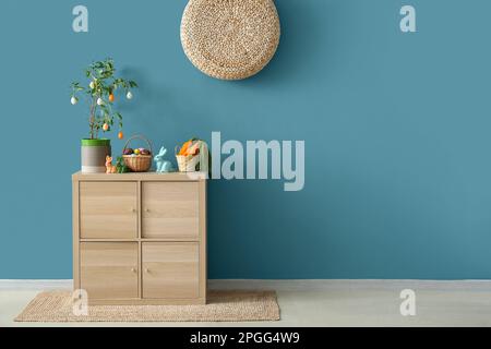 Decorazioni pasquali su armadio in legno vicino alle pareti blu Foto Stock