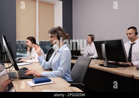 Operatori di contact centre con cuffie che lavorano in uffici moderni Foto Stock