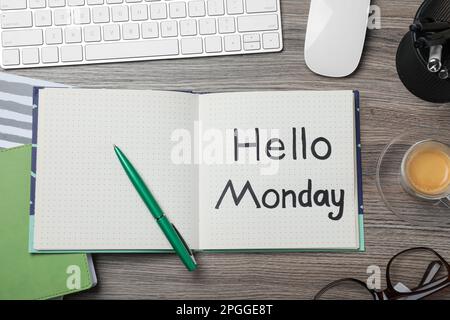 Messaggio Ciao Lunedi scritto in notebook, tastiera del computer e tazza di caffè su scrivania di legno, piatto Foto Stock