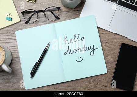 Messaggio Ciao Lunedi scritto in notebook, cancelleria e smartphone su scrivania di legno, piano Foto Stock