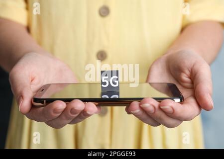 Tecnologia 5G, concetto Internet. Donna che tiene uno smartphone con carta, primo piano Foto Stock