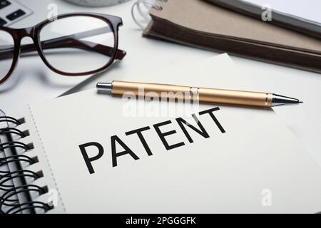 Quaderno con parola BREVETTO e penna su tavolo, primo piano Foto Stock