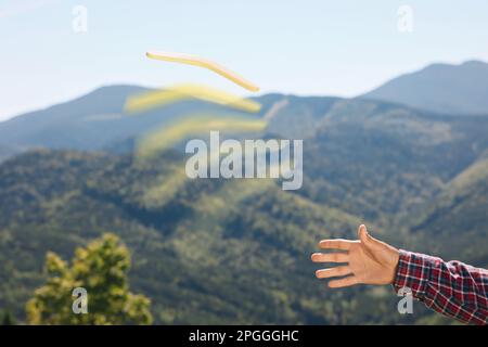 Uomo che lancia boomerang in montagna, vista primo piano Foto Stock