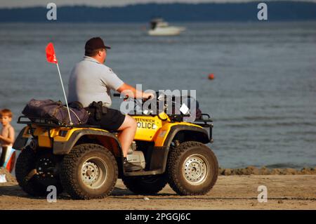 Un poliziotto pattuglia la costa su un quad durante una giornata di vacanze estive Foto Stock