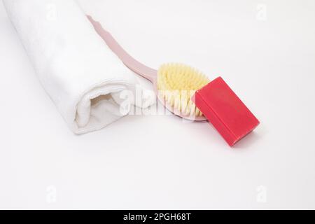 Asciugamano arrotolato con spazzola di lavaggio e sapone rosa su sfondo bianco isolato. Pulizia, cura. Spazio di copia Foto Stock