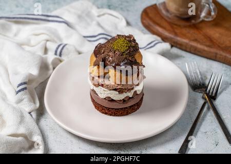 Torta a strati di profiteroles. Panna montata, cioccolato e torta al pistacchio. Foto Stock
