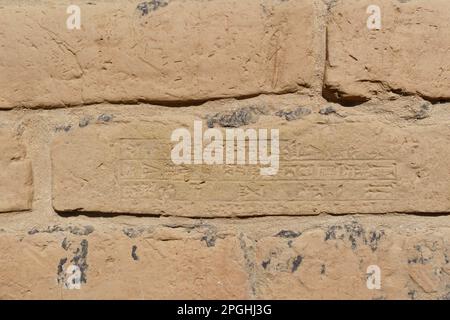 Babilonia, Iraq - 11 febbraio 2023: Vista ravvicinata di un mattone da parete su cui è inciso in una sceneggiatura cuneiforme babilonese. Foto Stock