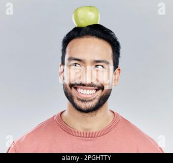 Felice, sano e un uomo asiatico che pensa ad una mela isolata su uno sfondo bianco in uno studio. Sorriso, idea e un ragazzo cinese con un frutto per Foto Stock