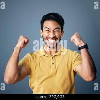 Uomo indiano, festeggiamenti eccitati e ritratto in studio per vincere mentalità, felicità o realizzazione da sfondo. Modello giovane, studente maschio o. Foto Stock